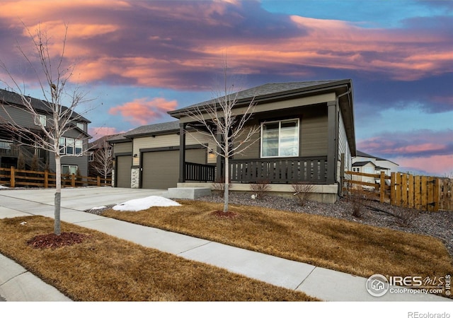 view of front of property featuring a garage, driveway, a porch, and fence