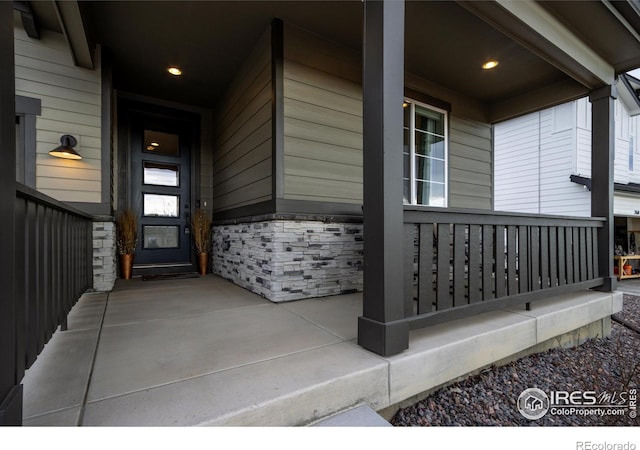 doorway to property with stone siding and covered porch