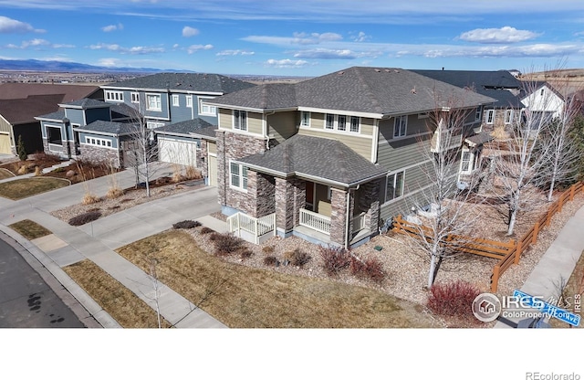 view of front of house featuring driveway, a shingled roof, stone siding, a residential view, and a porch