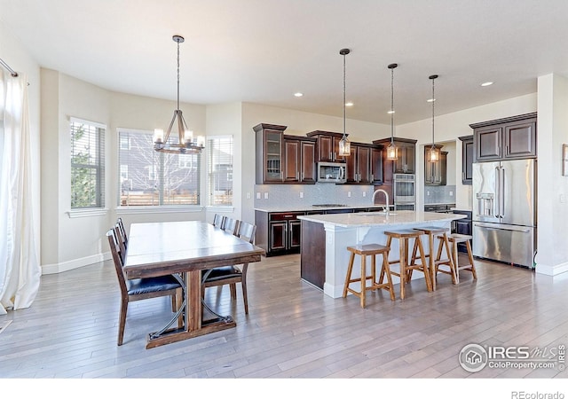 dining space featuring baseboards, recessed lighting, light wood-type flooring, and an inviting chandelier