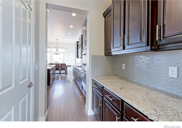 kitchen with recessed lighting, wood finished floors, decorative backsplash, dark brown cabinetry, and light stone countertops