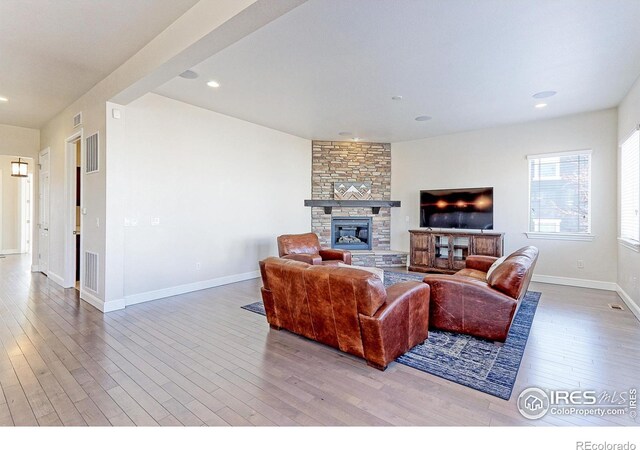 living area featuring a fireplace, wood finished floors, visible vents, and baseboards