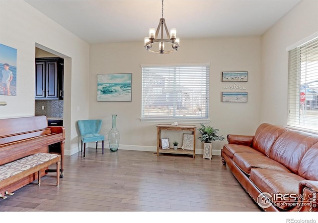 sitting room with light wood-style floors, a notable chandelier, and baseboards