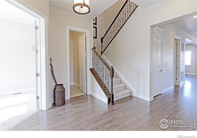 entryway featuring stairs, wood finished floors, and baseboards