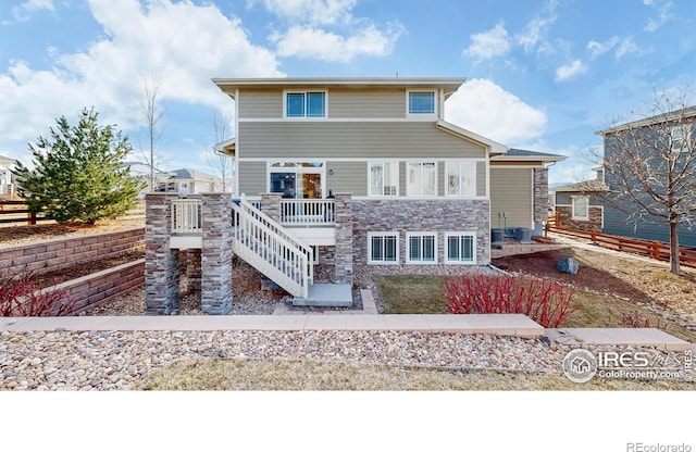 rear view of property with stone siding, stairs, and a deck