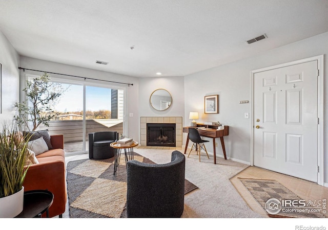 carpeted living room with a fireplace, visible vents, and baseboards