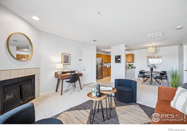 living area featuring a tile fireplace, visible vents, light carpet, and baseboards