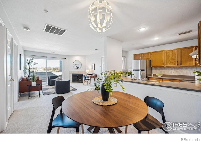 dining room with recessed lighting, a fireplace, visible vents, and light colored carpet