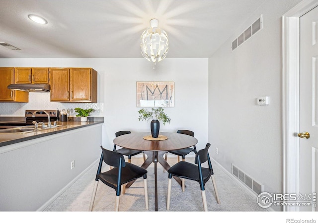 carpeted dining room featuring a sink, visible vents, and baseboards