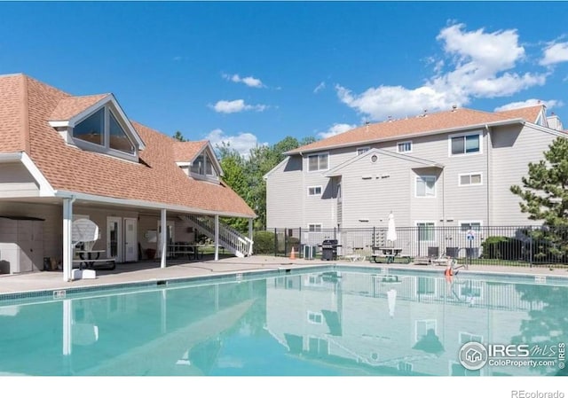 pool with a patio area and fence