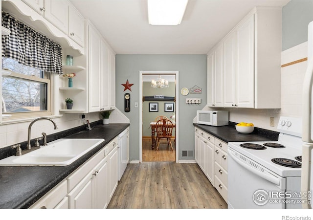 kitchen with white cabinets, visible vents, a sink, white appliances, and tasteful backsplash