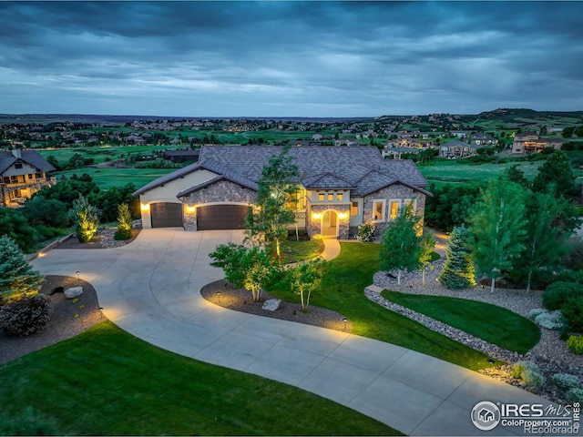 french provincial home featuring a garage, stone siding, concrete driveway, and a front yard