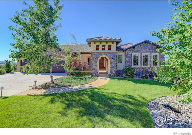 mediterranean / spanish house with stucco siding, concrete driveway, an attached garage, a tiled roof, and a front lawn