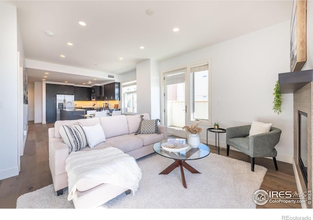 living area with recessed lighting, baseboards, a glass covered fireplace, and light wood finished floors