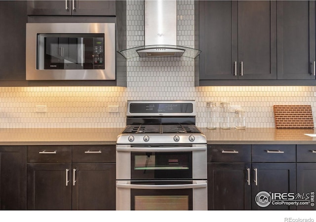 kitchen featuring stainless steel appliances, wall chimney exhaust hood, backsplash, and light countertops