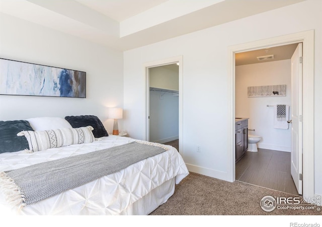 bedroom with baseboards, visible vents, a walk in closet, dark carpet, and a closet