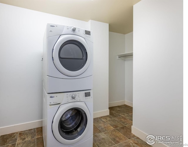 laundry room with laundry area, baseboards, and stacked washing maching and dryer