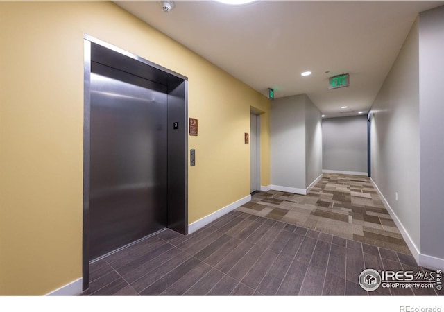 hallway with elevator, baseboards, and recessed lighting