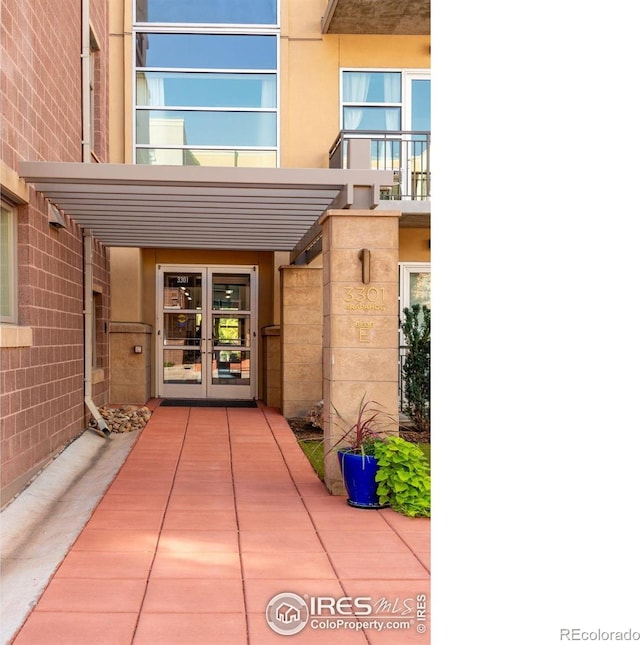 doorway to property featuring french doors, a balcony, and stucco siding