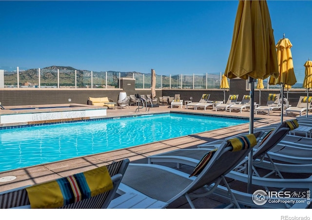 community pool featuring a patio, fence, and a mountain view