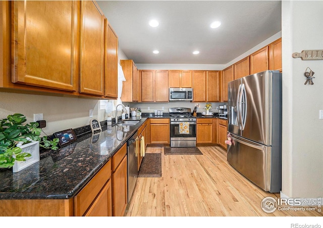 kitchen with brown cabinets, recessed lighting, appliances with stainless steel finishes, a sink, and light wood-type flooring