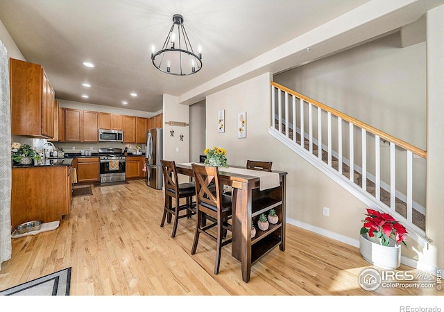 dining area with a notable chandelier, recessed lighting, light wood-style flooring, baseboards, and stairs