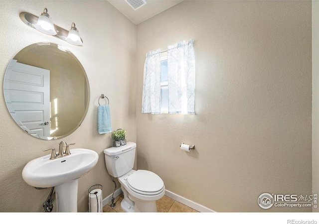 bathroom featuring visible vents, baseboards, toilet, tile patterned floors, and a sink