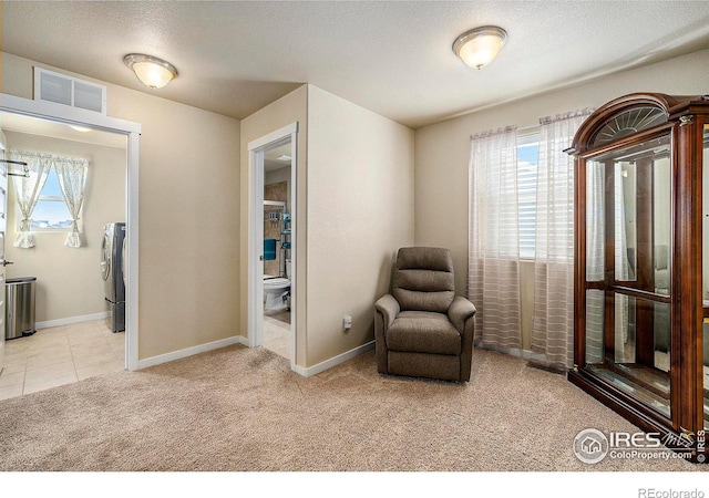 living area featuring light carpet, baseboards, visible vents, and a textured ceiling