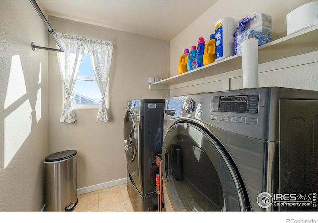 washroom featuring baseboards, laundry area, light tile patterned floors, and washer and dryer