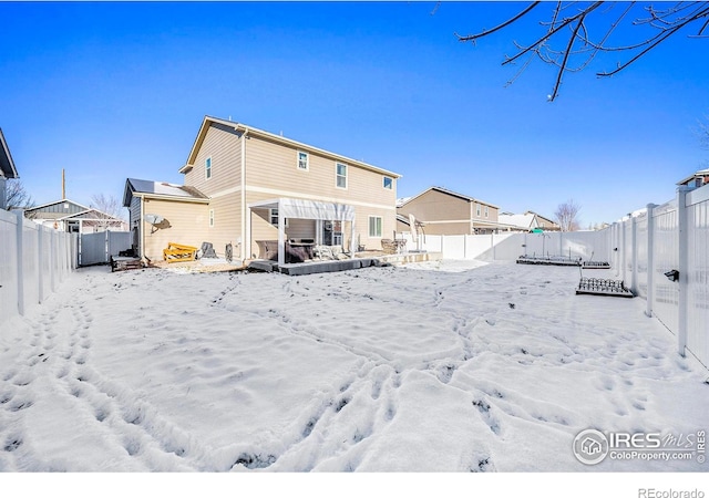 snow covered back of property with a fenced backyard