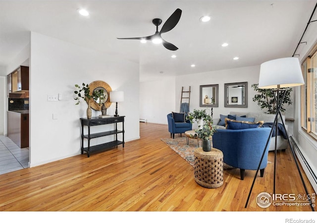 living room featuring light wood finished floors, baseboard heating, and recessed lighting