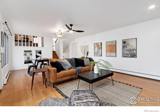 living room with a ceiling fan, a baseboard radiator, stairs, baseboard heating, and light wood-type flooring