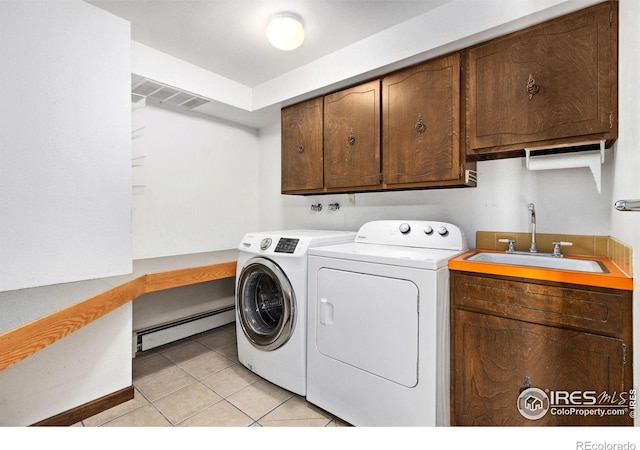 laundry room featuring cabinet space, light tile patterned floors, washer and clothes dryer, baseboard heating, and a sink