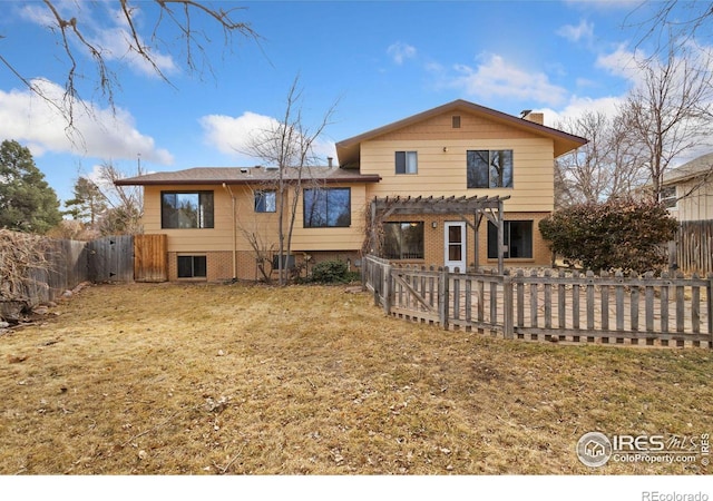 rear view of house with brick siding, a chimney, a lawn, a pergola, and a fenced backyard