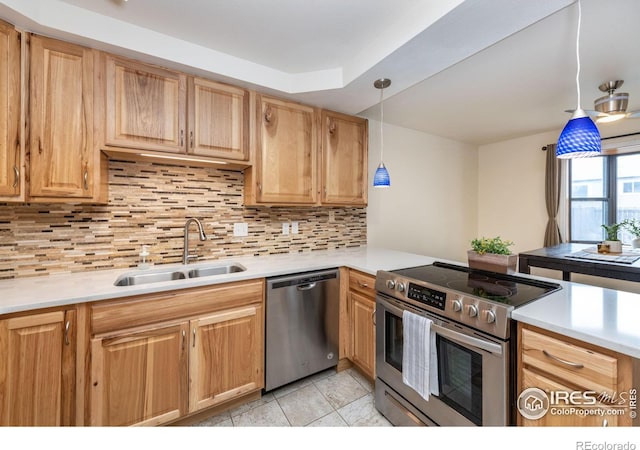 kitchen featuring decorative backsplash, decorative light fixtures, stainless steel appliances, light countertops, and a sink