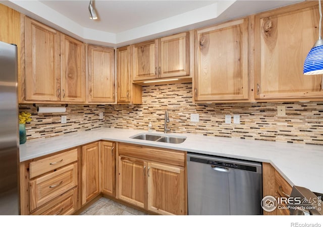 kitchen with tasteful backsplash, stainless steel appliances, a sink, and light countertops