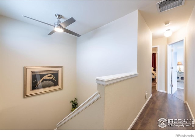 hall featuring baseboards, visible vents, an upstairs landing, and wood finished floors