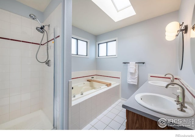 bathroom with a stall shower, tile patterned flooring, a skylight, and a sink