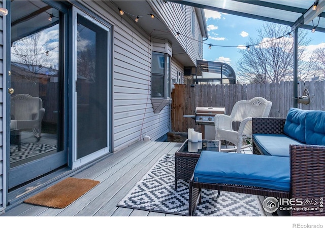 wooden terrace with area for grilling, fence, and an outdoor living space