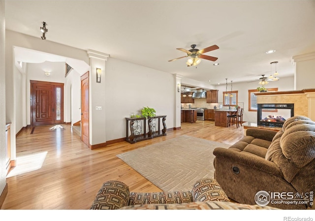 living room with light wood finished floors, recessed lighting, a ceiling fan, a multi sided fireplace, and baseboards