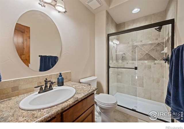 bathroom with toilet, vanity, a shower stall, and visible vents