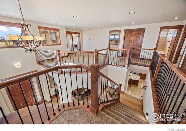 staircase with recessed lighting, an inviting chandelier, and wood finished floors