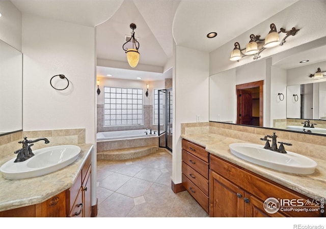 bathroom featuring a garden tub, two vanities, a sink, and tile patterned floors