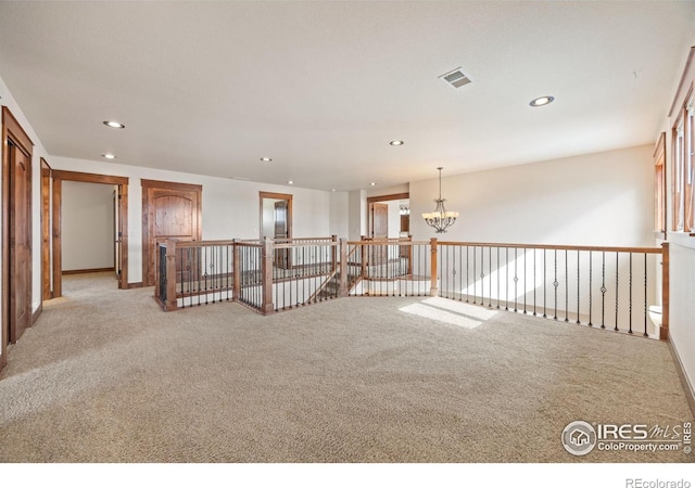 unfurnished room with light carpet, recessed lighting, and a notable chandelier