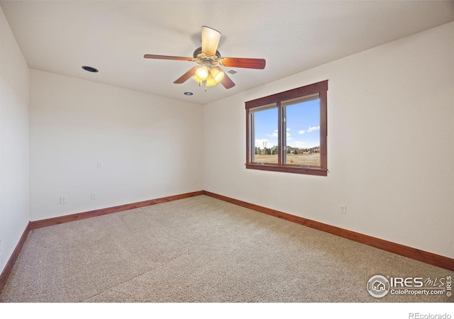 carpeted empty room with a ceiling fan and baseboards