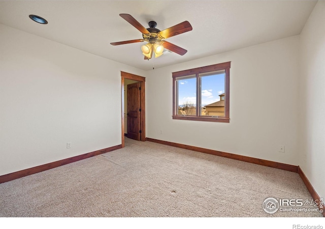 spare room featuring a ceiling fan, light colored carpet, and baseboards