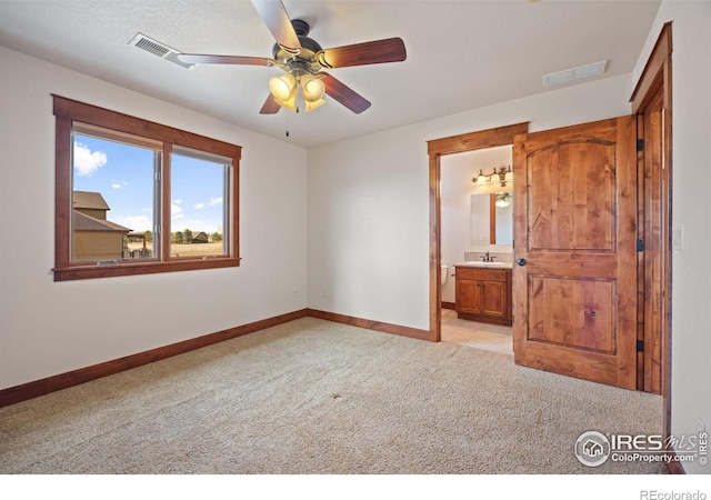 unfurnished bedroom featuring light colored carpet, visible vents, ensuite bathroom, a sink, and baseboards