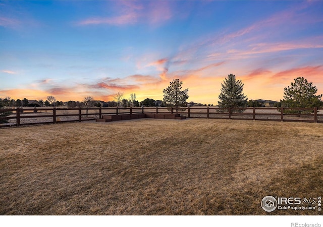 yard at dusk with a rural view and fence