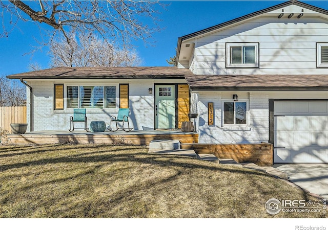 view of front of house featuring a porch, a front yard, brick siding, and fence