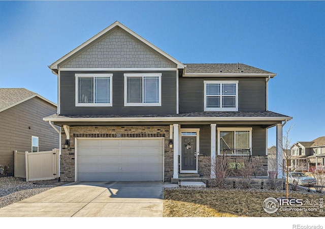 craftsman-style house featuring a garage, concrete driveway, stone siding, and fence